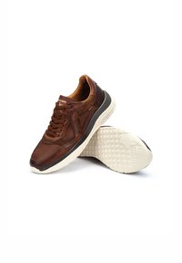 Zapatillas de cuero marrón con acentos de malla, puntera redonda, cuello acolchado y una suela de goma blanca con agarre texturizado.