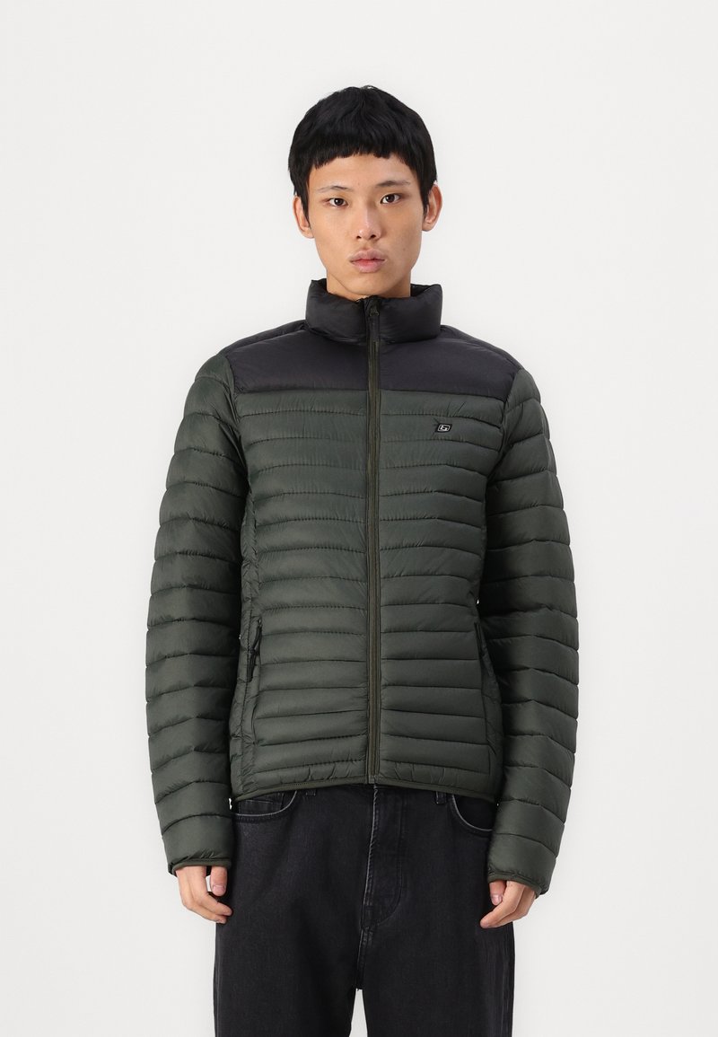 Grønne puffervest med sort skulder- og kraveområde. Har vandret quiltet design, frontlynlås og sidelommer.