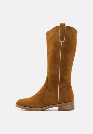 Brown suede knee-high boot with a smooth texture, featuring a white stitched accent and a low stacked heel for stability.