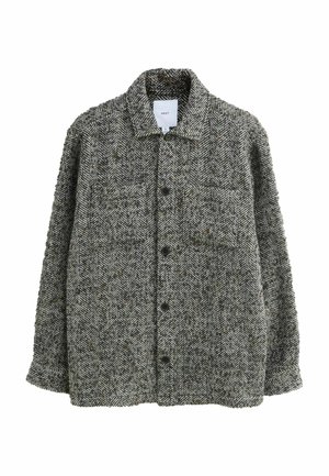 Harmaa ja musta kalanruotokuvioinen takki, joka on valmistettu tekstuurisesta kankaasta. Takissa on kauluspaita ja kaksi nappikiinnitteistä etutaskua.