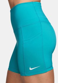Turkise høyhalsede Nike-shorts laget av elastisk stoff, med flate sømmer og en liten hvit Nike-logo nederst til venstre.