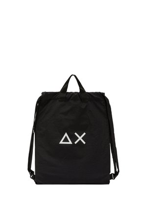 Zaino rettangolare nero con due manici corti e spallacci regolabili, con simboli bianchi a triangolo e X sulla parte anteriore.