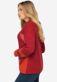 Gestrickter Pullover in Rottönen mit strukturierter Oberfläche. Mit langen Ärmeln und einer lockeren Passform. Farbverlauf von tiefrot zu orange.
