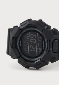 Digitálne hodinky Casio G-Shock v matnej čiernej farbe s obdĺžnikovým displejom a gumovým remienkom. Medzi funkcie patrí časovač, budík a vodoodolnosť do 20 barov.