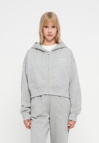 Siva skraćena zip-up hoodica od mekog pamuka, s prednjim džepom, rebrastim manžetama i bijelom logom na prsima.