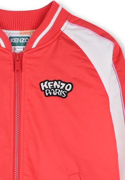 Giacca bomber rossa con colletto a costine, pannelli bianchi sulle maniche e logo nero ricamato "KENZO Paris" sul petto. Chiusura frontale con zip.