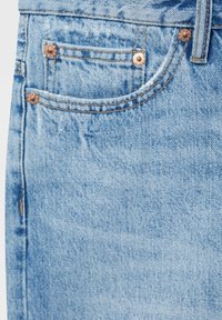 Ljusblå denimjeans med en framficka med kopparnitar, synlig sömnad och en något sliten textur.