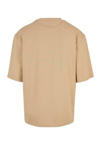 Tricou cu mânecă scurtă din bumbac bej, având o croială lejeră și gât rotund. Textură netedă, fără modele sau accente vizibile.