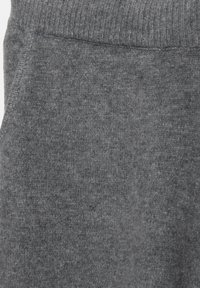 Tissu en polaire gris, avec une ceinture côtelée et une texture douce. Le design présente des variations subtiles d'ombrage et d'épaisseur.