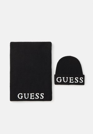 Juodas megztinis šalikas ir jam tinkantis kepurė, abu su balta "GUESS" logo. Minkšta tekstūra su raštuotais kraštais. Šalikas yra didesnis už kepurę.
