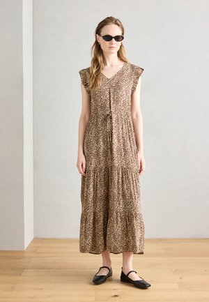 Vestito maxi leopardato marrone e beige con maniche a volant, vita con coulisse e design a strati; indossato con ballerine nere e occhiali da sole.