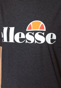 Gray short-sleeve t-shirt featuring a large white logo "ellesse" and a half orange and white circle design above the text. Soft fabric texture.