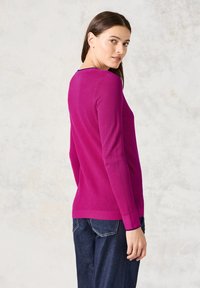 Maglione aderente a maniche lunghe in vivace fucsia, con un design a maglia testurizzato e polsini a costine. Collo girocollo classico e lunghezza media.