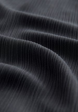 Fekete, texturált szövet, függőleges bordázattal, hullámos redőkkel és puha megjelenéssel. Ideális ruházathoz vagy kárpitozáshoz.