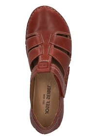 Red leather shoe with cut-out design, featuring white stitching and a textured upper. Interior shows brown leather lining. Adjustable strap included.