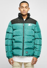 Teal puffer jacket with black shoulders, zip front, side pockets, and embroidered logo. Features a quilted design and elastic cuffs.