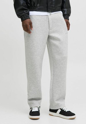 Grå sweatpants lavet af blødt stof, med en afslappet pasform, snor i taljen og sidelommer, parret med sorte sneakers.