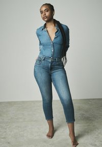 Jeans košulja s gumbićima sprijeda i tijesnim krojem, u kombinaciji sa skinny trapericama srednje pranja koje imaju skraćeni rub i suptilno izbjeljivanje.