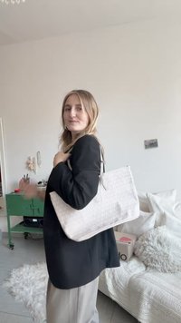 Hvit mønstret handlenett med en strukturert design og nøytral tone, med to skulderstropper og en jevn tekstur.