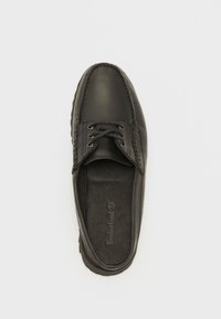 Chaussure en cuir noir avec lacets, bout arrondi et couture contrastante. La semelle intérieure texturée présente le logo Timberland. La semelle a un bord légèrement surélevé.