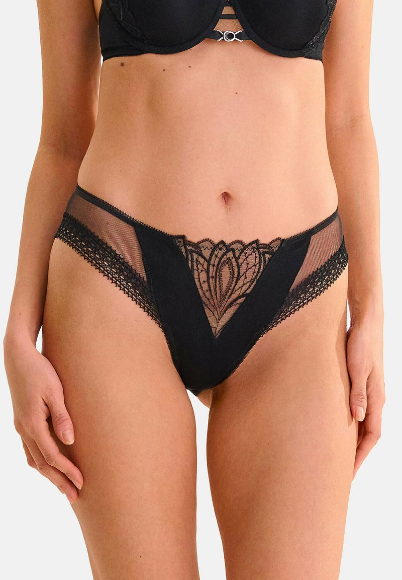 Zwarte kant en net onderkleding met bloemmotieven, een V-vormige uitsnijding aan de voorkant en een contrasterende textuur tailleband.