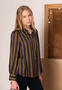 Hemd zum Zumknöpfen mit vertikalen olivgrünen und marineblauen Streifen, lockerer Passform und abgerundetem Saum. Das Material wirkt glatt und möglicherweise leicht glänzend.