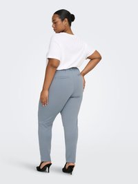 Light gray fitted pants with a stretchy waistband, side pockets, and a smooth texture, paired with a plain white short-sleeve top.