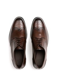 Braune Leder-Oxfords mit Broguemuster, ausgestattet mit einer polierten Oberfläche, runder Zehenpartie und Schnürdesign. Tapered-Form und strukturierte Details.