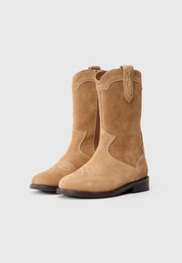Stivali ankle in suede marrone chiaro con dettagli ricamati sulla punta, zip laterale e linguetta nella parte superiore. Suola piatta in gomma.