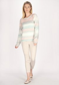 Pulover cu dungi pastelate într-un tricot moale și ușor. Are o guler rotund și mâneci lungi, asortat cu pantaloni bej deschis, ajustați și pantofi bej.