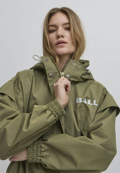 Olīvu zaļš parka ar elastīgām piedurknēm, regulējamu kapuci, priekšējo rāvējslēdzēju un balti izdrukātu "BALL" logotipu uz krūšu kabatas.