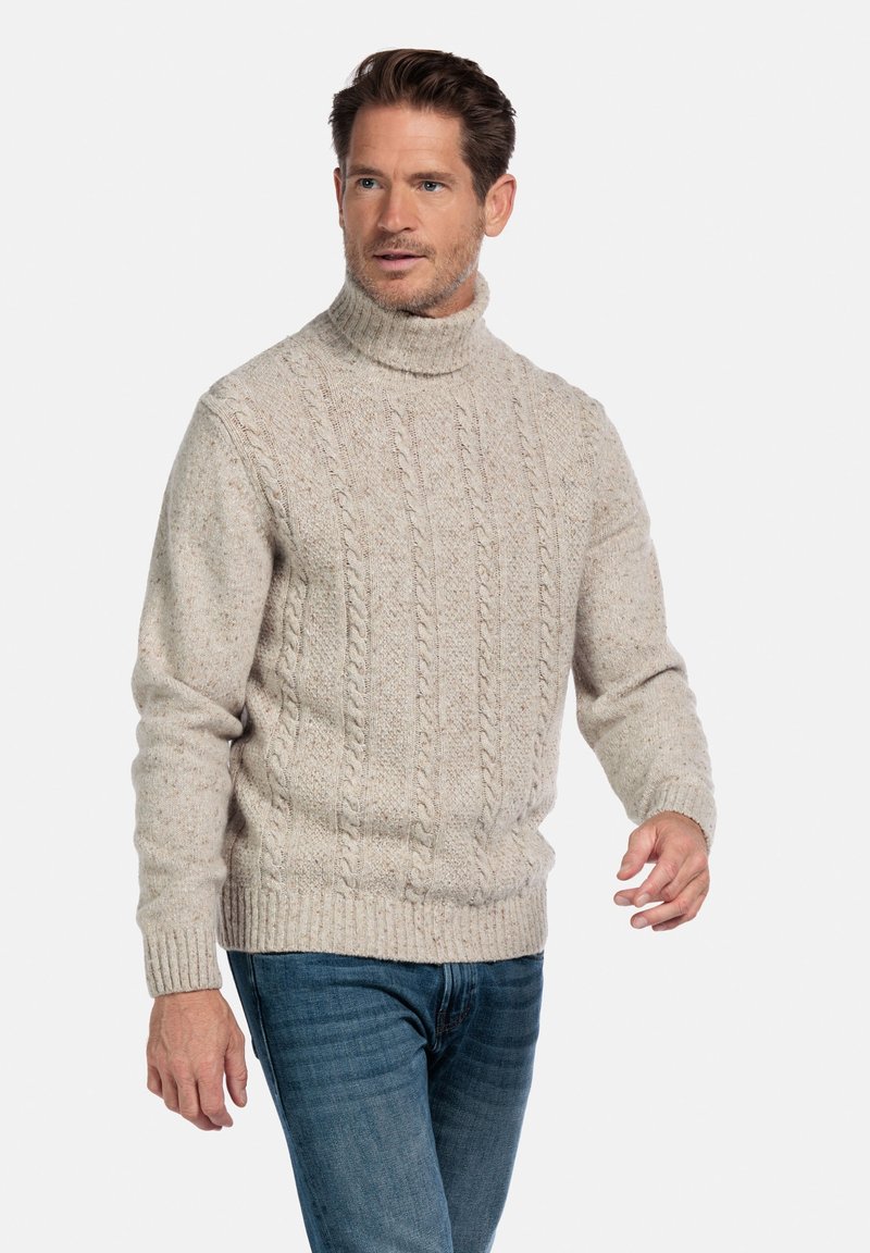 Lichtbeige kabelgebreide coltrui met geribbelde manchetten en zoom, met een textuurafwerking, gedragen met blauwe jeans.