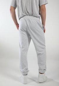 Graue Sweatpants mit elastischem Bund und Bündchen, aus weichem Stoff, mit Seitentaschen und lockerer Passform. Getragen mit weißen Sneakers.