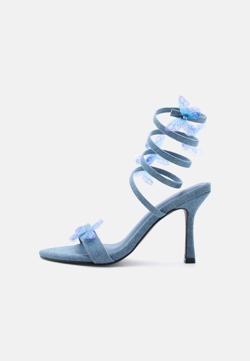 Sandale à talon haut bleu clair avec bride spirale à la cheville et décorations translucides en forme de papillon bleu sur les brides des orteils et des chevilles.