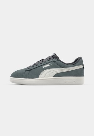 Sneaker in suede grigio con logo Puma bianco, dotate di un design a taglio basso, punta rotonda e suola in gomma bianca. Dettagli di cucitura minimalista.