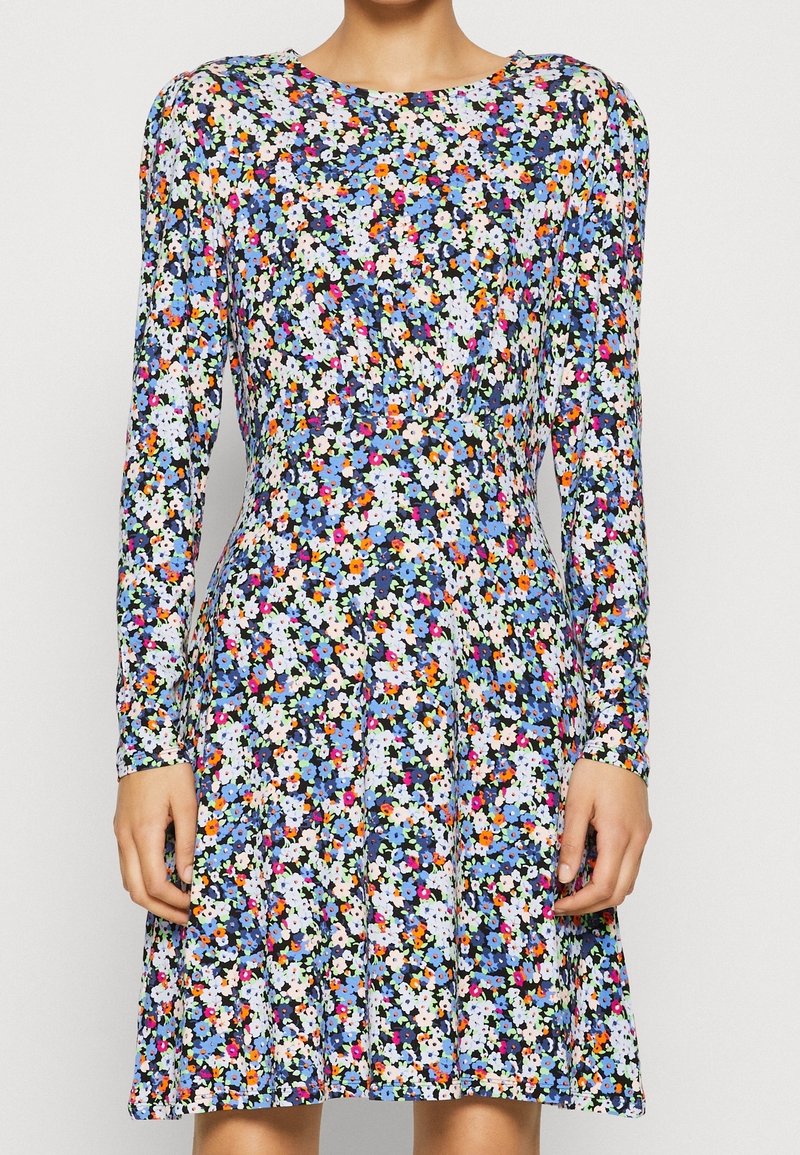 Kwiecista sukienka z długim rękawem, z granatowym tłem i wielobarwnymi kwiatami, dopasowaną talią oraz rozkloszowanym dołem, wykonana z lekkiego materiału.