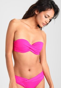 Horká růžová bandeau bikiny vršek s designem se zkroucením vpředu, doplněný o nízké kalhotky. Hladká textura, elastický materiál.