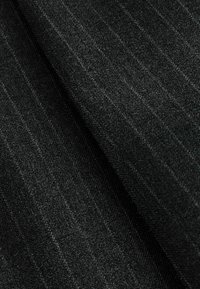 Tessuto nero con una finitura testurizzata, caratterizzato da sottili strisce verticali. Il materiale appare morbido e leggermente peloso al tatto.