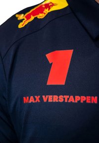 Granatowy sweter z dużą czerwoną cyfrą "1" oraz imieniem "MAX VERSTAPPEN" w pogrubionym czerwonym tekście, wykonany z teksturowanej tkaniny.