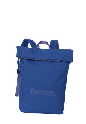 Blue backpack with a zippered top, made of durable fabric. Features a large compartment, padded shoulder straps, and a subtle brand logo.