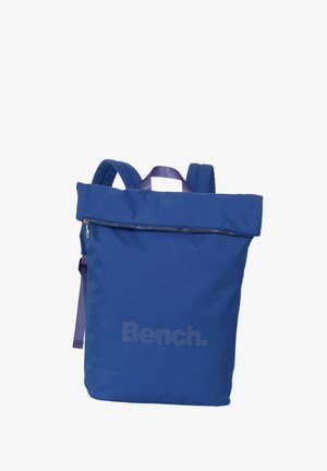 Blue backpack with a zippered top, made of durable fabric. Features a large compartment, padded shoulder straps, and a subtle brand logo.