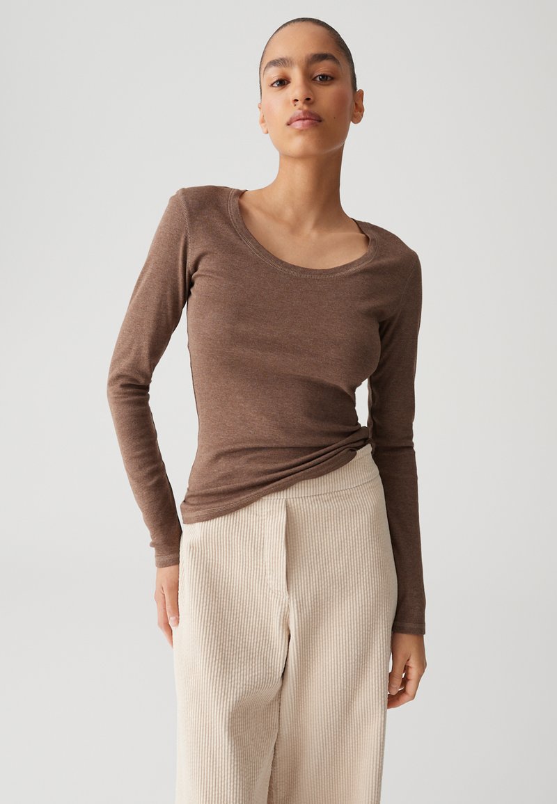 Brown long-sleeve shirt in a lightweight, soft fabric with a rounded neckline, paired with textured cream-colored wide-leg pants.