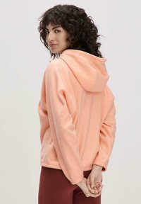 Fleece-Hoodie in hellem Pfirsich mit Kängurutasche und verstellbarem Kordelzug an der Kapuze. Mit lockerer Passform und gerippten Bündchen.