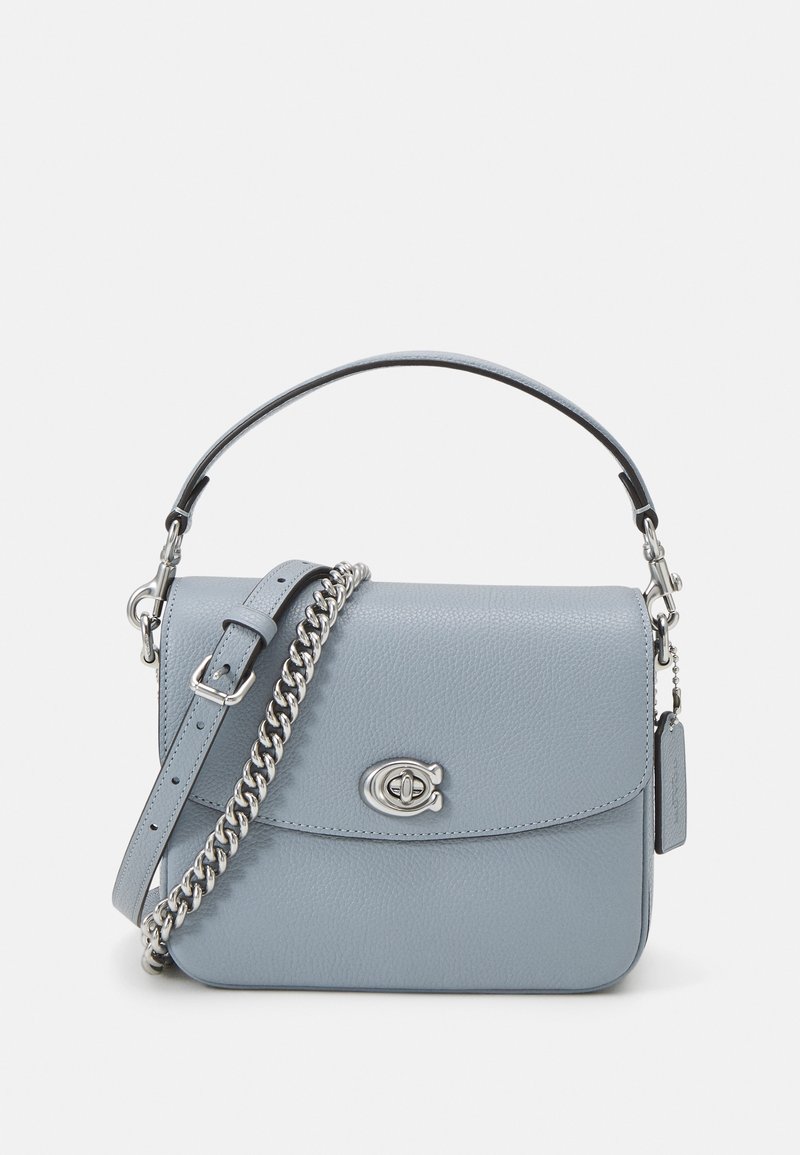 Sac à main en cuir bleu clair avec fermoir à verrou argenté, une courte poignée et une bandoulière amovible avec un détail chaîne argentée.