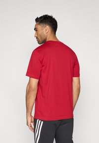 Punane lühikeste varrukatega t-särk, mis on valmistatud puuvillasegukangast, ümmarguse kaelusega, lõdva istuvusega, õlgadel ja äärel nähtavate õmblustega.