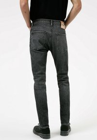 Černé džínové skinny kalhoty s vybledlým povrchem, pěti kapsami a koženou nášivkou značky na zadním pásu. Texturovaná tkanina, slim fit.