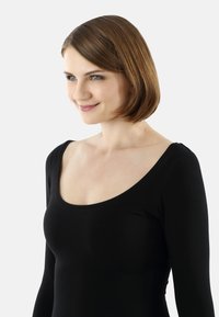 Black long-sleeve top with a scoop neckline, made of smooth fabric. Model has short brown hair, facing slightly to the right. Simple design.