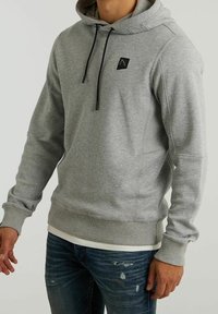 Sudadera gris con capucha, cordones y un pequeño logo negro. Presenta puños y dobladillo acanalados, y una tela suave y texturizada.
