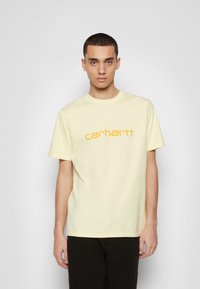 T-shirt de algodão amarelo com um corte descontraído e mangas curtas, com o logótipo "carhartt" em destaque em laranja no peito.
