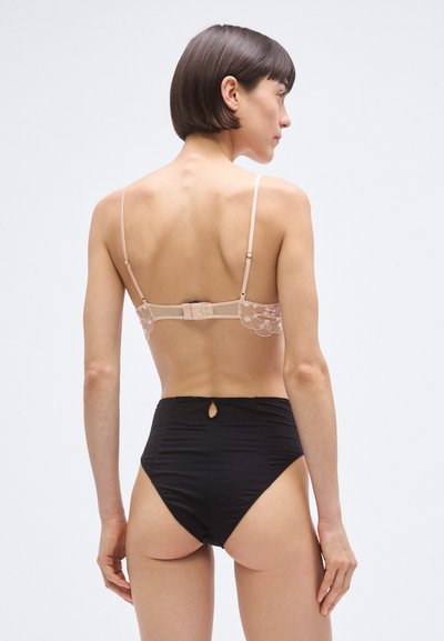 Világos rózsaszín csipke melltartó állítható pántokkal, magas derekú fekete bugyival párosítva, melynek hátul kulcslyuk részlete van.